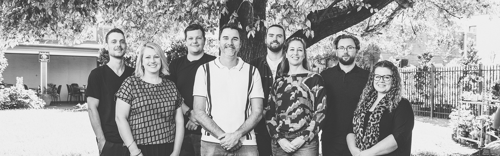 The Team at Handmade Web and Design outside their office smiling under a large tree
