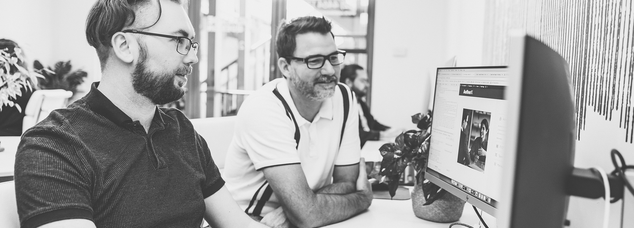 Two Handmade Web and Design Employees focusing on a computer screen, reviewing their work
